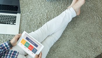 A person with crossed legs, holding an iPad that says 'scholarships' on it