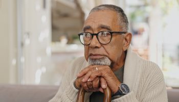Depressed looking senior man on sofa in living room of retirement home