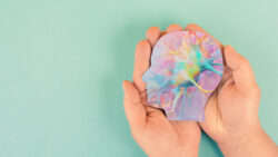Hands holding a model of a human head, printed with an image of a neuron