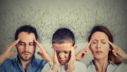 a man, woman, and child grip their temples while black fuzz rises from their heads, signifying some form of mental stress or illness