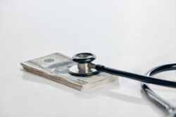A stethoscope rests on a stack of dollar bills. Learn more about how to get rehab without insurance here.
